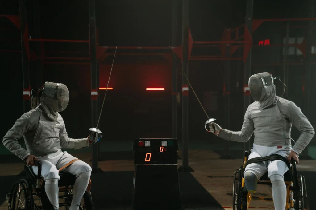 Adaptability Skills :Two wheelchair fencers in full gear face each other in a match, demonstrating adaptability skills through competitive para-sport.