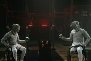 Adaptability Skills :Two wheelchair fencers in full gear face each other in a match, demonstrating adaptability skills through competitive para-sport.