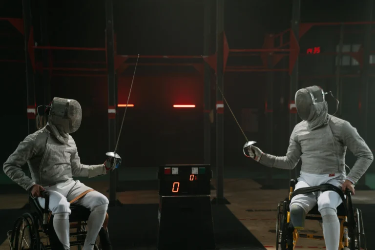 Adaptability Skills :Two wheelchair fencers in full gear face each other in a match, demonstrating adaptability skills through competitive para-sport.